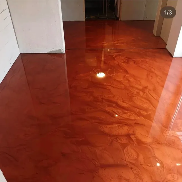 Blank epoxybelagt gulv i dyp rød farge med marmorert effekt mellom rom.