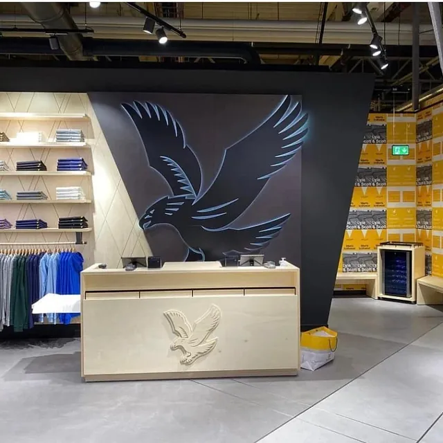 Klesbutikk med fuglelogo på mørk vegg og grått betonggulv.