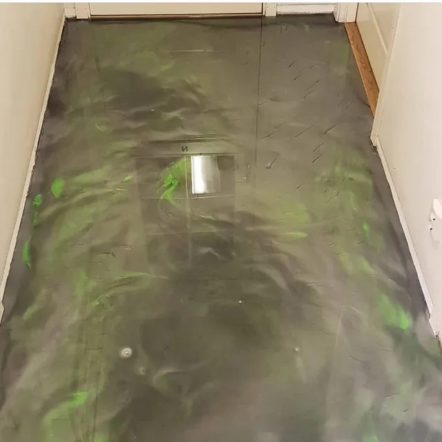 Gang med mørkgrått epoxygulv og grønne skimrende effekter i overflaten.